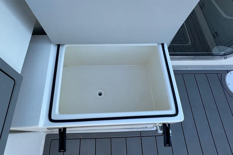 Slide: The Image of Open storage compartment on 2025 Defiance Admiral 250 EX boat, featuring a drain hole. - 44