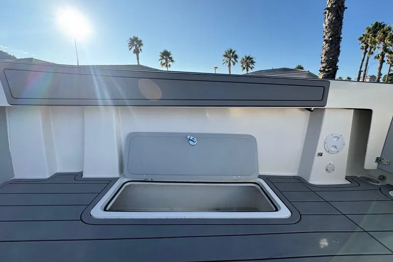 Slide: The Image of 2025 Defiance Admiral 250 EX boat deck with open storage compartment, under sunny sky. - 48