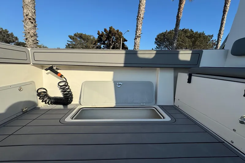 Slide: The Image of 2025 Defiance Admiral 250 EX boat deck with storage compartment and coiled hose. - 49