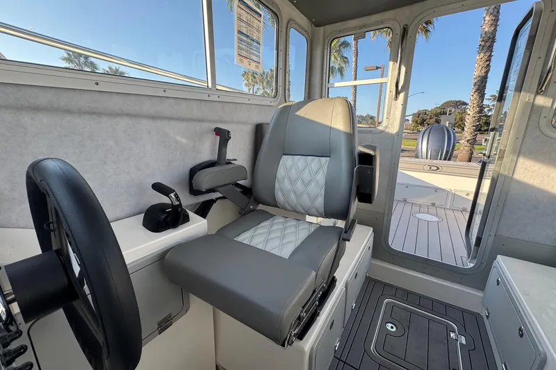 Slide: The Image of Interior of 2025 Defiance Admiral 250 EX boat, featuring captain's seat and control panel. - 76