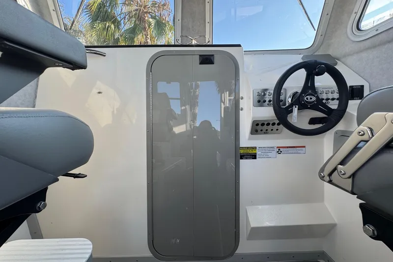 Slide: The Image of Interior of 2025 Defiance Admiral 250 EX boat, featuring steering wheel and seating. - 87