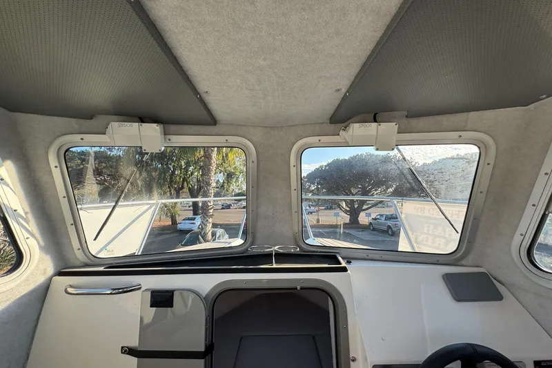 Slide: The Image of Interior view of 2025 Defiance Admiral 250 EX boat cabin with windows and controls. - 92