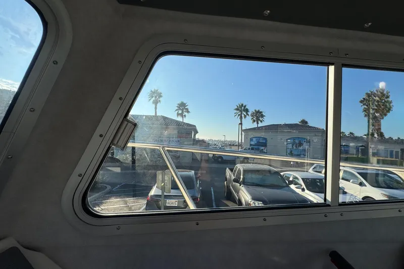 Slide: The Image of View from Defiance Admiral 250 EX boat window, showcasing parked cars and palm trees, 2025 model. - 94