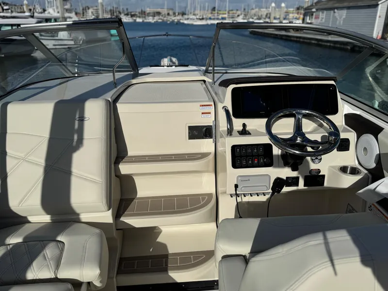 Slide: The Image of 2025 Regal 26 XO boat interior with steering wheel, dashboard, and seating, docked at marina. - 52