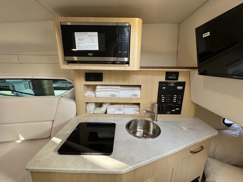 Slide: The Image of 2025 Regal 26 XO boat interior with kitchenette, microwave, sink, and storage shelves. - 59