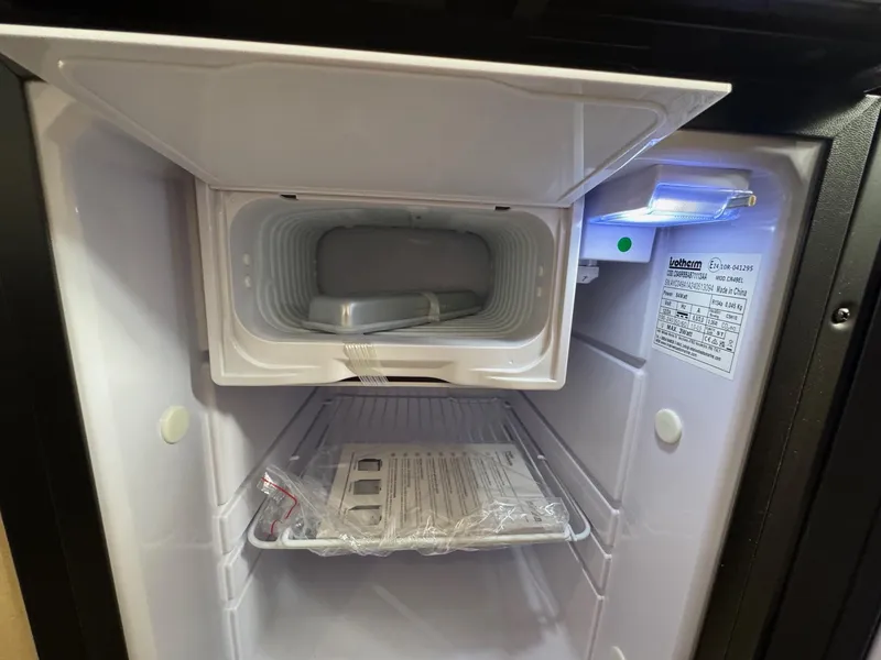 Slide: The Image of Open mini fridge interior with freezer compartment in a 2025 Regal 26 XO boat. - 64