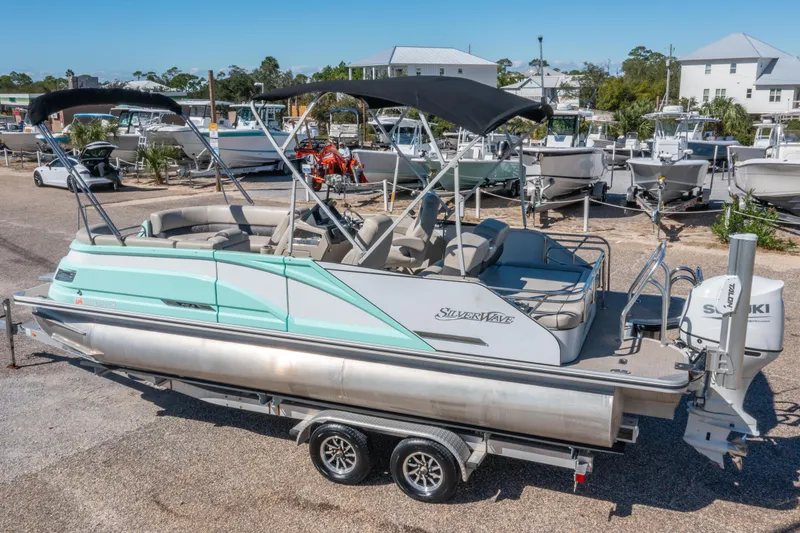 Slide: The Image of 2021 Silver Wave 2410 SW5 JS pontoon boat on trailer, parked in marina. - 2