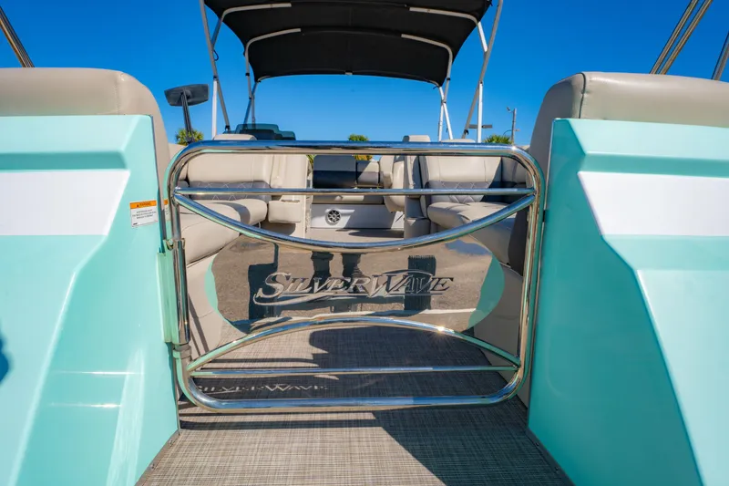 Slide: The Image of 2021 Silver Wave 2410 SW5 JS boat interior with seating and logo, under clear blue sky. - 24