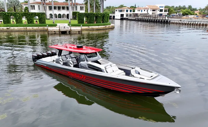 Slide: The Image of 2022 Nor-Tech 50 Sport boat with red accents on a calm waterfront. - 34