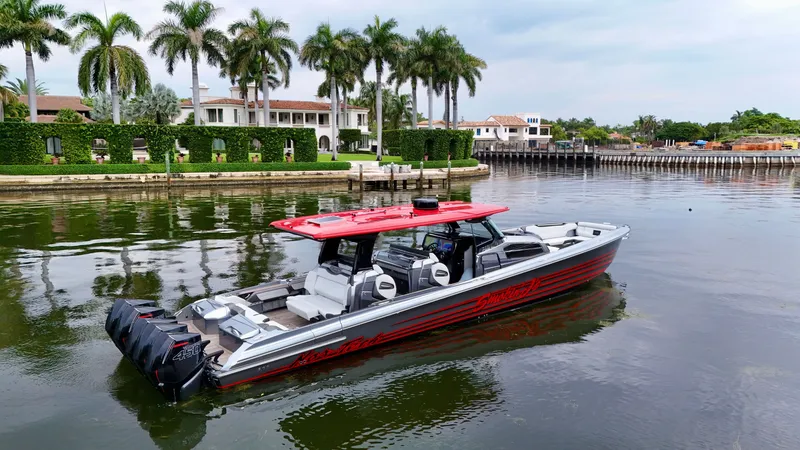 Slide: The Image of 2022 Nor-Tech 50 Sport boat with red roof on calm water, palm trees in background. - 8