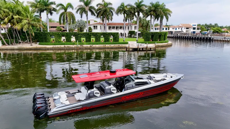 Slide: The Image of 2022 Nor-Tech 50 Sport boat with red roof, docked near luxury waterfront homes and palm trees. - 9