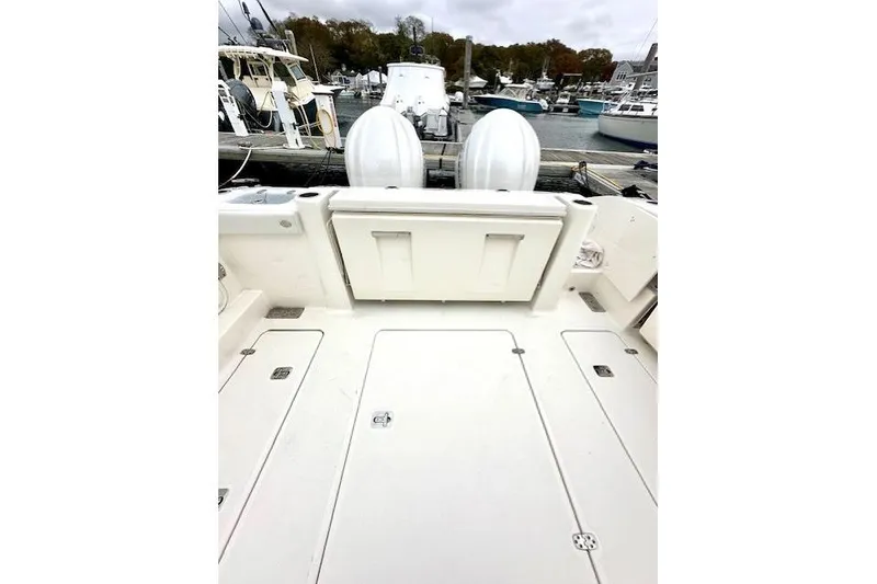 Slide: The Image of 2024 Pursuit DC 326 Dual Console boat deck with twin engines at marina. - 6