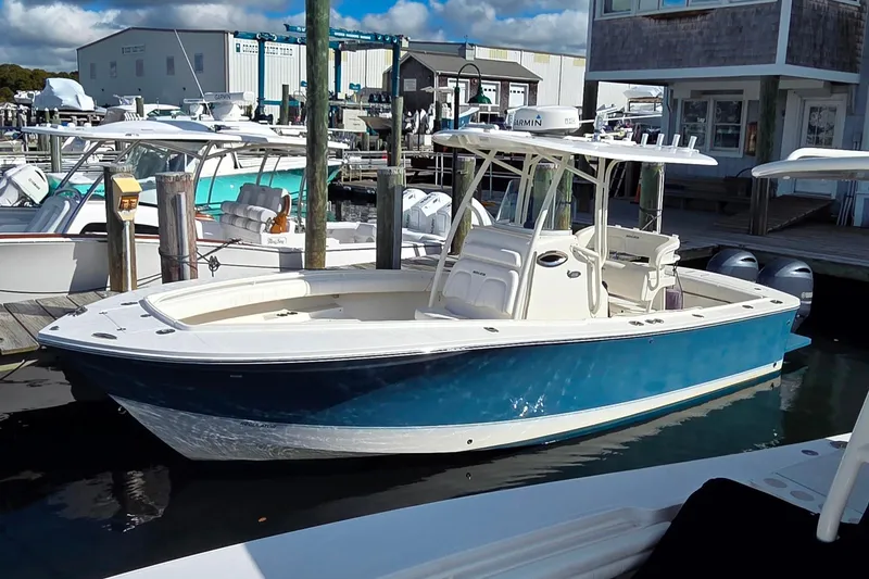 The Image of 2014 Regulator 25 boat docked at marina, featuring blue hull and white interior. - 0