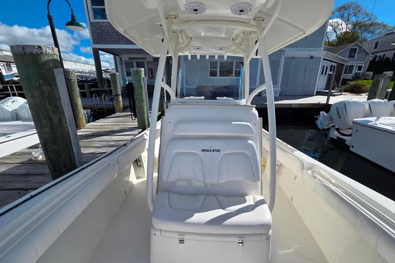 Slide: The Image of 2014 Regulator 25 boat interior at dock, featuring white seating and console. - 14