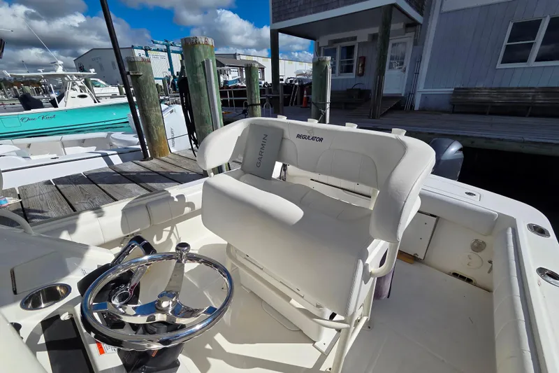 Slide: The Image of 2014 Regulator 25 boat interior with steering wheel and seating at dock. - 6
