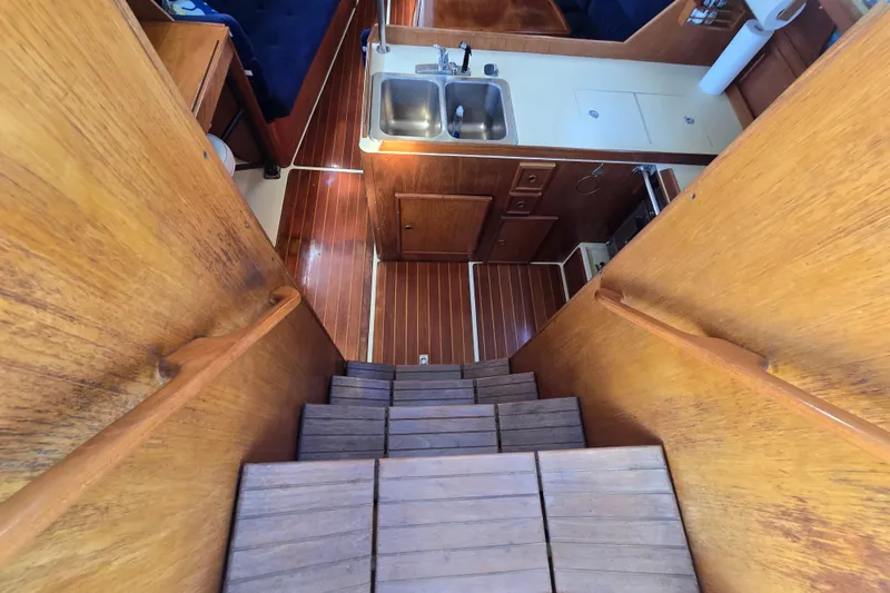Slide: The Image of Interior of 1988 Pearson 362 Centerboard sailboat, featuring wooden stairs and compact kitchen area. - 12