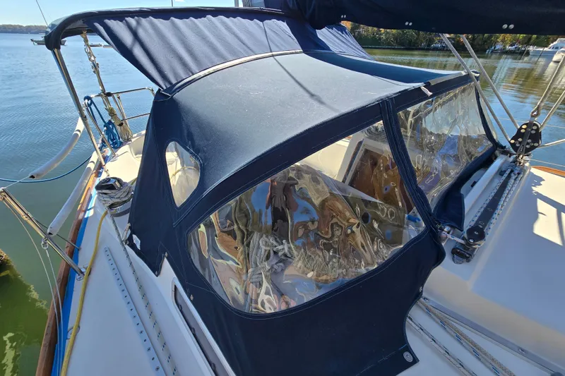 Slide: The Image of 1988 Pearson 362 Centerboard sailboat with blue canvas cover on deck, docked by calm waters. - 27