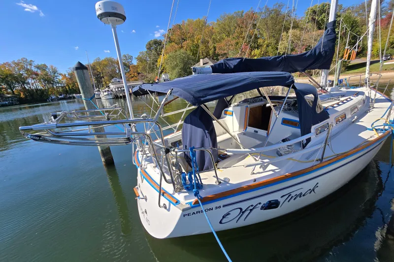 Slide: The Image of 1988 Pearson 362 Centerboard sailboat docked, featuring blue canvas covers and scenic autumn backdrop. - 30