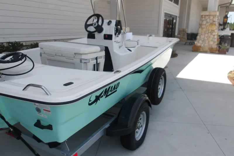 Slide: The Image of 2026 Mako Pro Skiff 15 CC boat on trailer, parked near a building. - 58