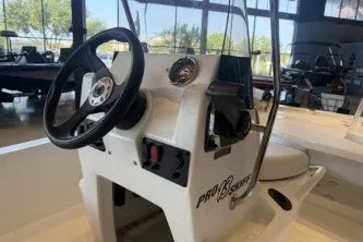Slide: The Image of 2026 Mako Pro Skiff 13 CC boat console with steering wheel in showroom. - 15