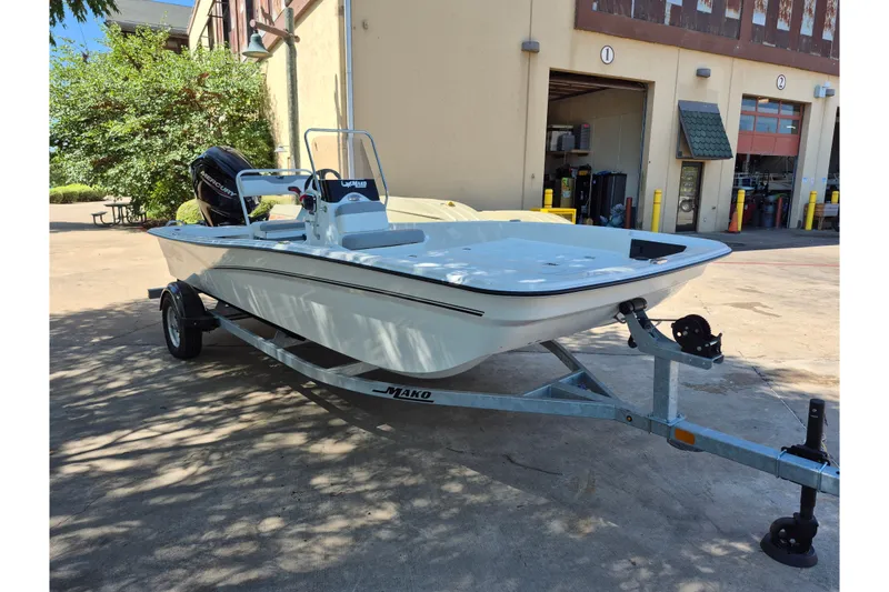 Slide: The Image of 2026 Mako Pro Skiff 17 CC boat on trailer outside a garage. - 3