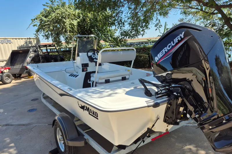Slide: The Image of 2026 Mako Pro Skiff 17 CC boat with Mercury engine, parked outdoors. - 7