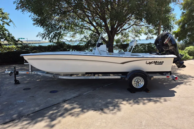 The Image of 2026 Mako Pro Skiff 17 CC boat on trailer, parked outdoors under a tree. - 0