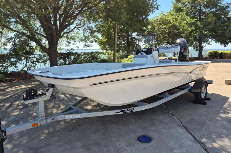 Slide: The Image of 2026 Mako Pro Skiff 17 CC boat on trailer, parked outdoors near trees. - 1