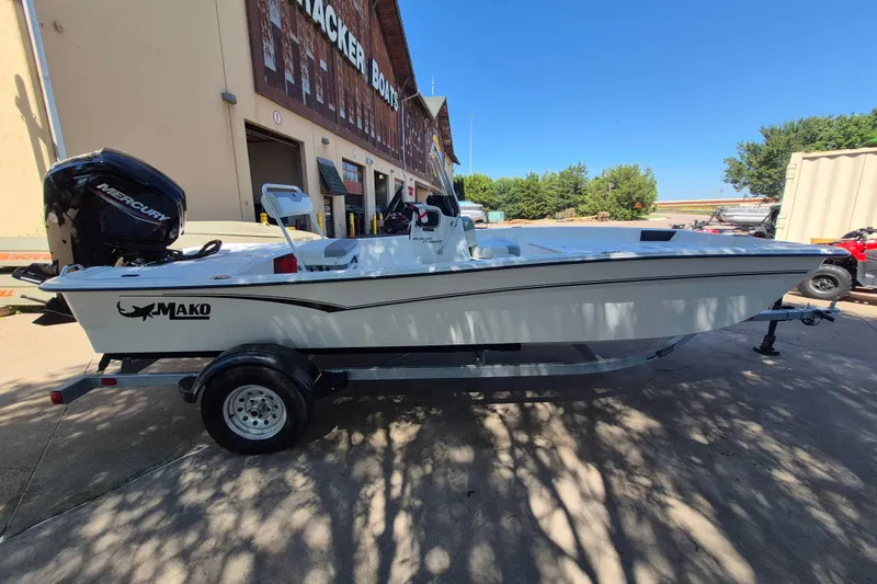 Slide: The Image of 2026 Mako Pro Skiff 17 CC boat on trailer, parked outside a building under clear blue sky. - 4