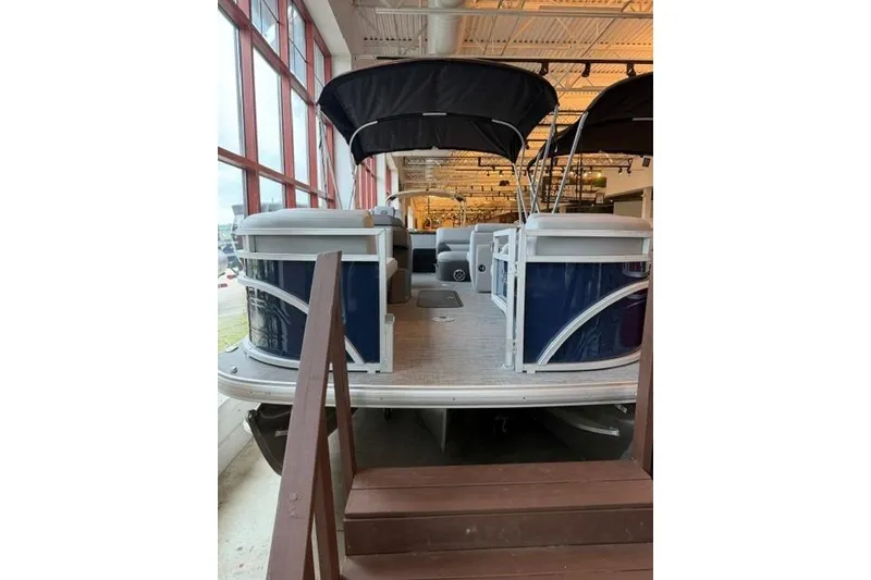 Slide: The Image of 2026 Sun Tracker SportFish 22 XP3 pontoon boat displayed indoors with canopy. - 1