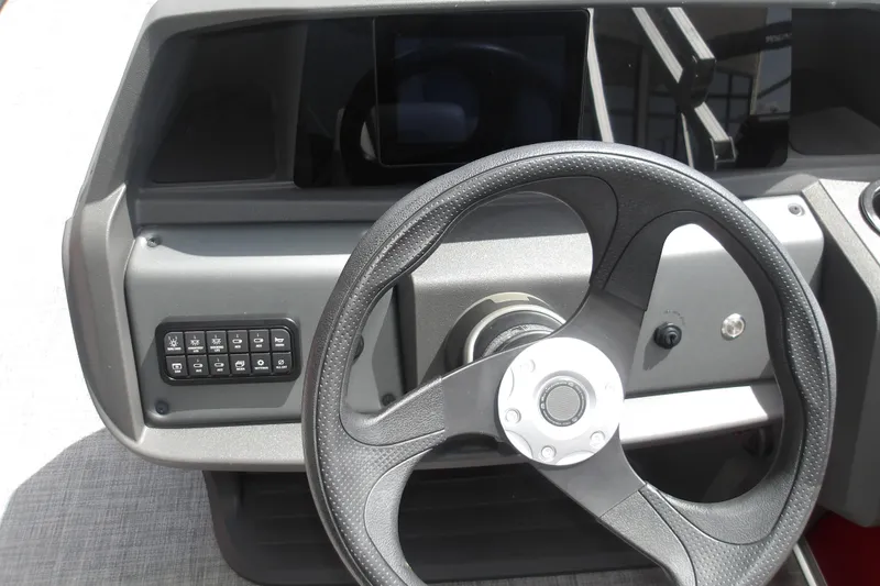 Slide: The Image of Steering console of 2026 Sun Tracker Party Barge 18 DLX with control panel and wheel. - 18