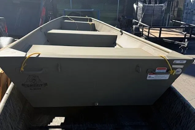Slide: The Image of 2026 Tracker Grizzly 14 Jon boat in a parking lot, showcasing its sturdy design. - 4