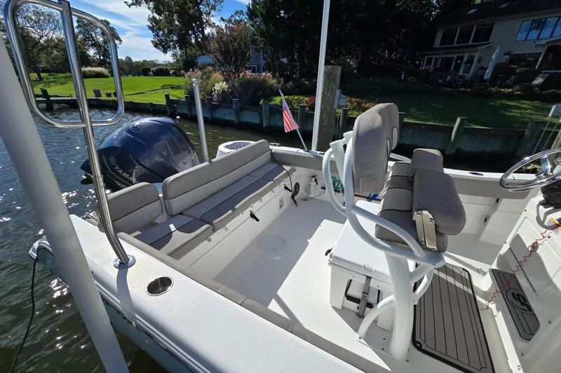 Slide: The Image of 2022 Sea Fox 249 Avenger boat interior with seating and Yamaha engine, docked by waterfront homes. - 12
