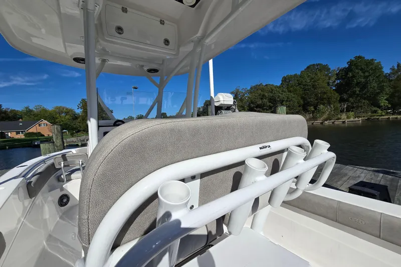 Slide: The Image of 2022 Sea Fox 249 Avenger boat interior with rod holders, docked by a scenic shoreline. - 23