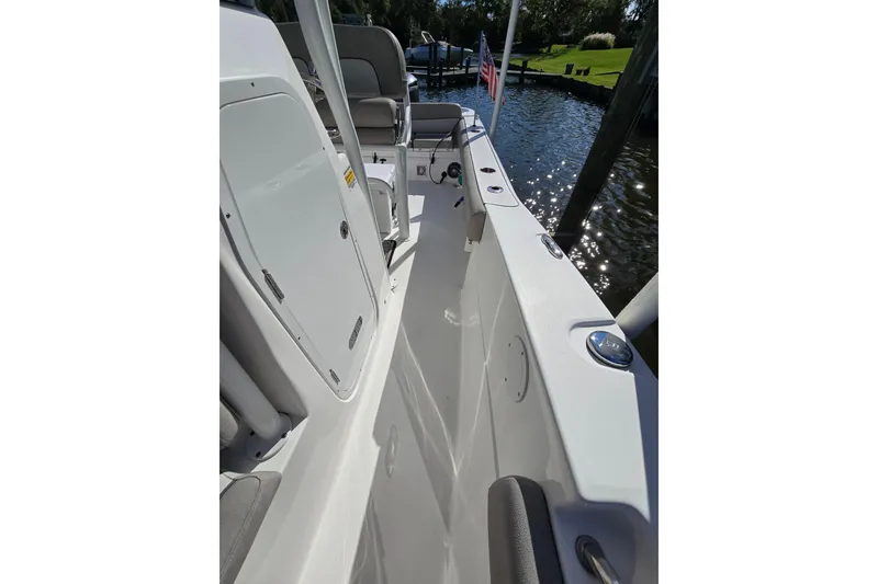 Slide: The Image of 2022 Sea Fox 249 Avenger boat interior with seating and storage, docked by the water. - 41