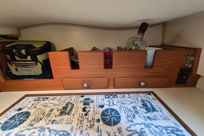 Slide: The Image of Wooden storage area in a 2001 Island Packet 420 yacht, featuring compartments and nautical-themed mat. - 37