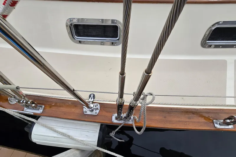 Slide: The Image of 2001 Island Packet 420 sailboat deck with rigging and ropes, docked by a calm river. - 8