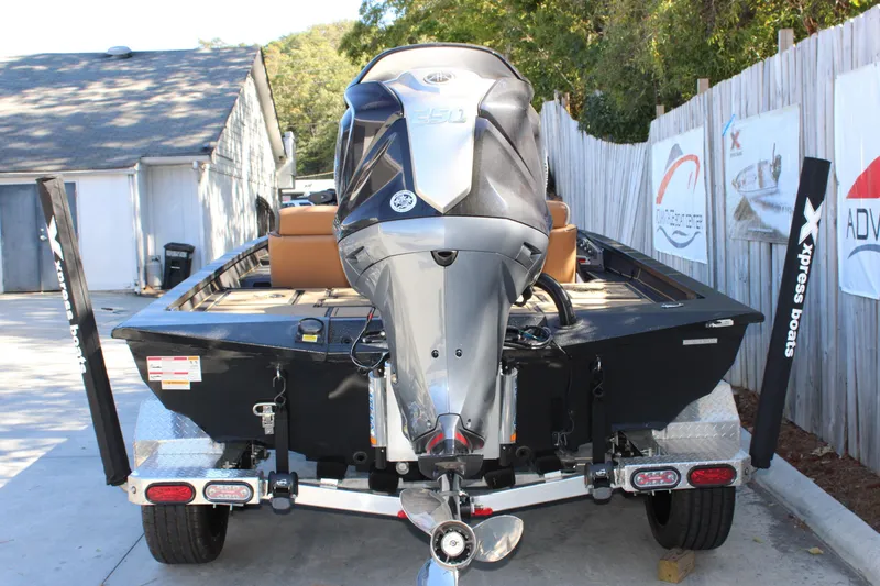 Slide: The Image of Xpress X21 Pro 2026 boat on trailer, rear view with motor, outdoor setting. - 4