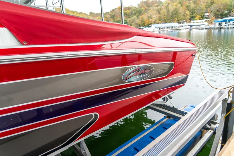 Slide: The Image of Red 2000 Baja 36 Outlaw boat docked on a lake with scenic background. - 16