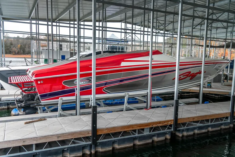 Slide: The Image of Red 2000 Baja 36 Outlaw speedboat docked in a marina under a metal canopy. - 3