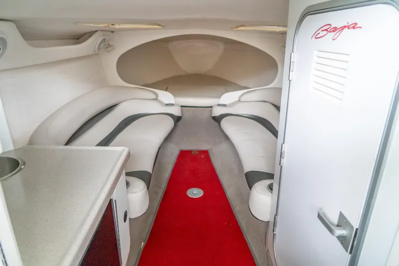 Slide: The Image of Interior of a 2000 Baja 36 Outlaw boat with red carpet and white seating. - 41