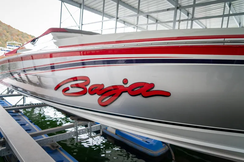 Slide: The Image of 2000 Baja 36 Outlaw boat with red and blue stripes docked in a marina. - 5