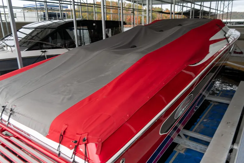 Slide: The Image of 2000 Baja 36 Outlaw boat with red and gray cover in a marina. - 9