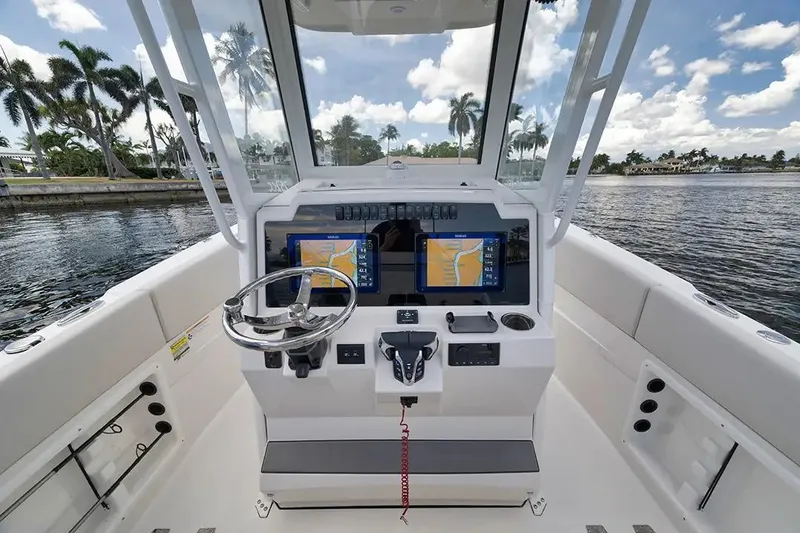 Slide: The Image of Manufacturer Provided Image: 2026 Sailfish 252 CC boat cockpit with dual navigation screens and steering wheel, docked by palm trees. - 6