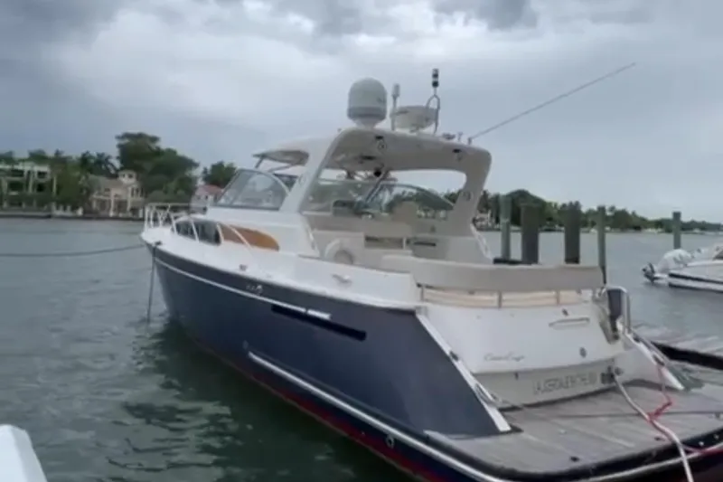 The Image of 2006 Chris-Craft 43 Roamer yacht on water, with palm trees and luxury homes in background. - 0