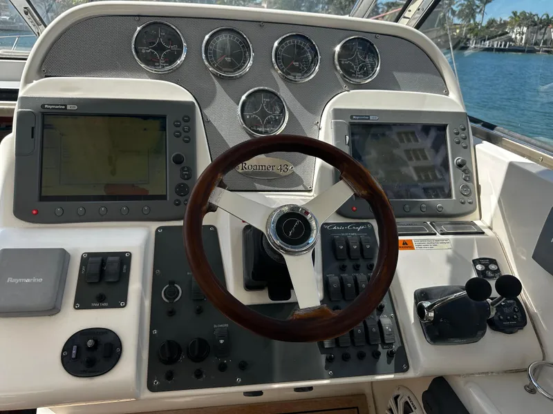 Slide: The Image of 2006 Chris-Craft 43 Roamer helm with dual navigation screens and classic wooden steering wheel. - 10
