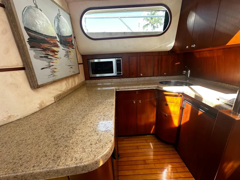 Slide: The Image of Luxurious kitchen interior of 2006 Chris-Craft 43 Roamer yacht with wood cabinetry and modern appliances. - 25