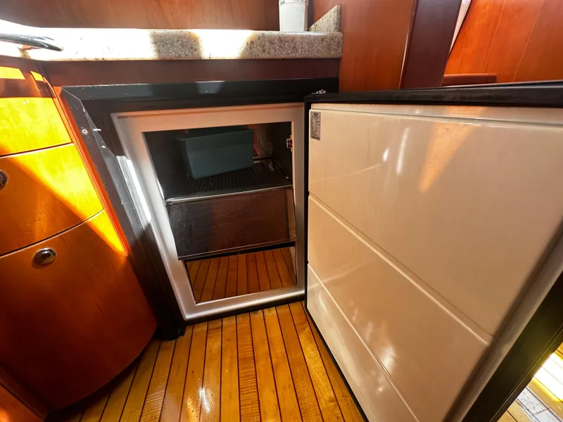 Slide: The Image of 2006 Chris-Craft 43 Roamer yacht interior with open mini fridge and wooden flooring. - 31