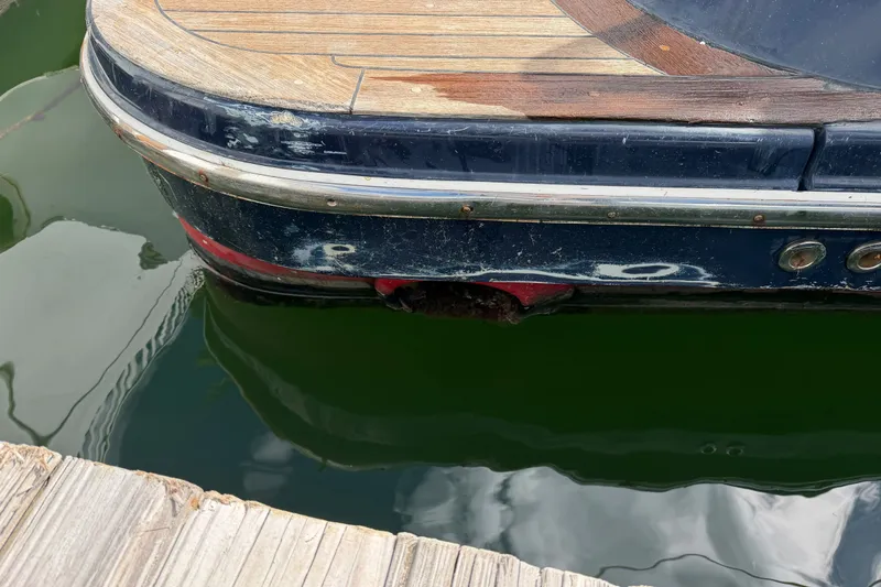 Slide: The Image of 2006 Chris-Craft Roamer 40 boat docked, showing weathered wooden deck and blue hull. - 39