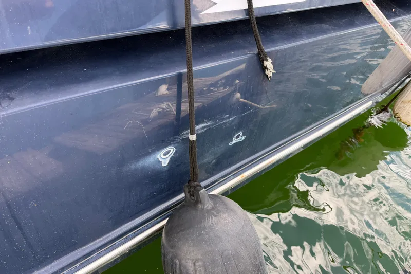 Slide: The Image of 2006 Chris-Craft Roamer 40 boat hull with dock fender, reflecting water surface. - 43